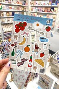 Sheet of stickers with various illustrations held in front of a store shelf.