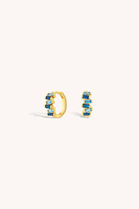 Gold hoop earrings with blue gemstones on a white background