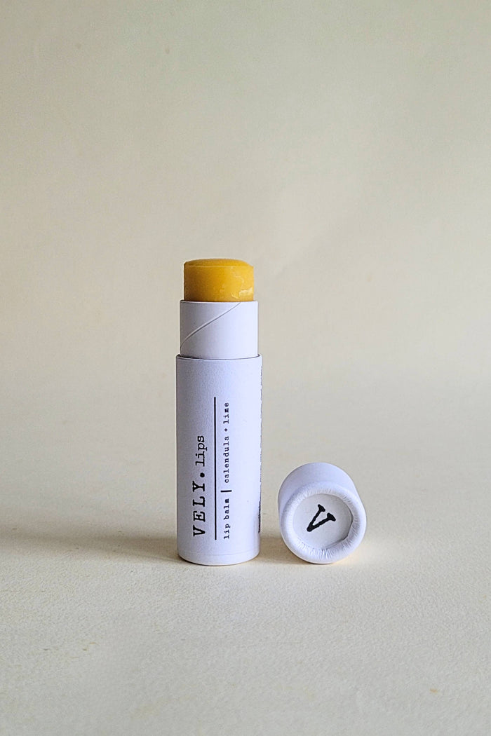 Lip balm with white container and yellow cap on a light beige background