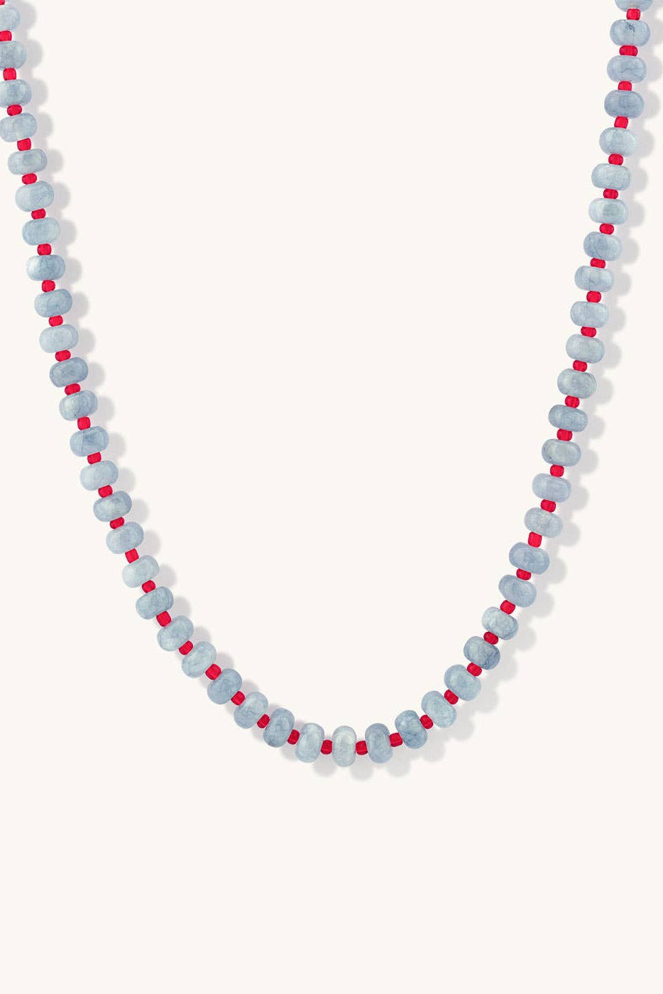 A beaded necklace featuring light blue-gray round beads separated by small bright red spacer beads, displayed against a clean off-white background.
