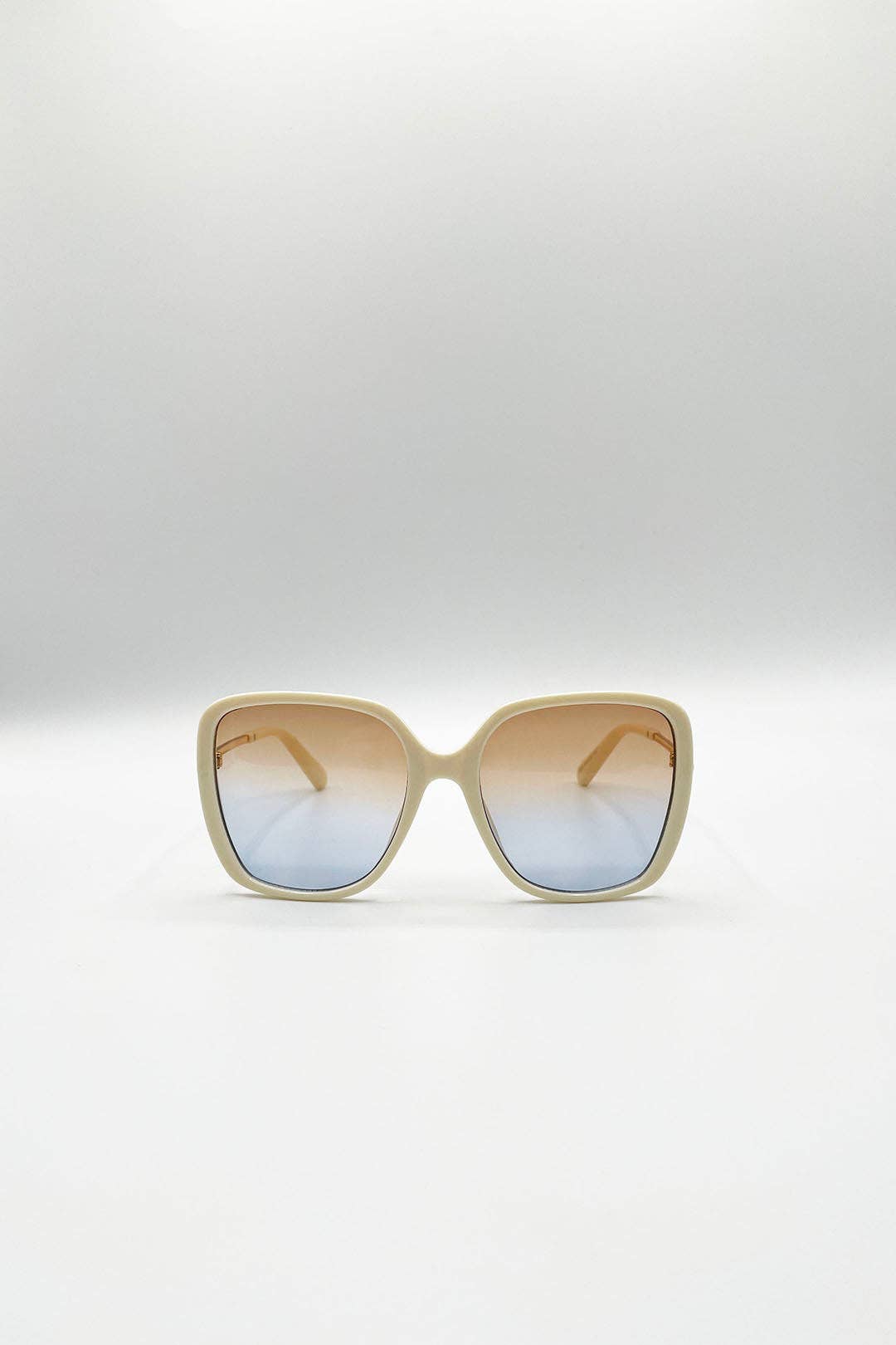 Oversized square sunglasses with a beige frame and gradient lenses that fade from warm tan at the top to light blue at the bottom, shown on a neutral light gray background.