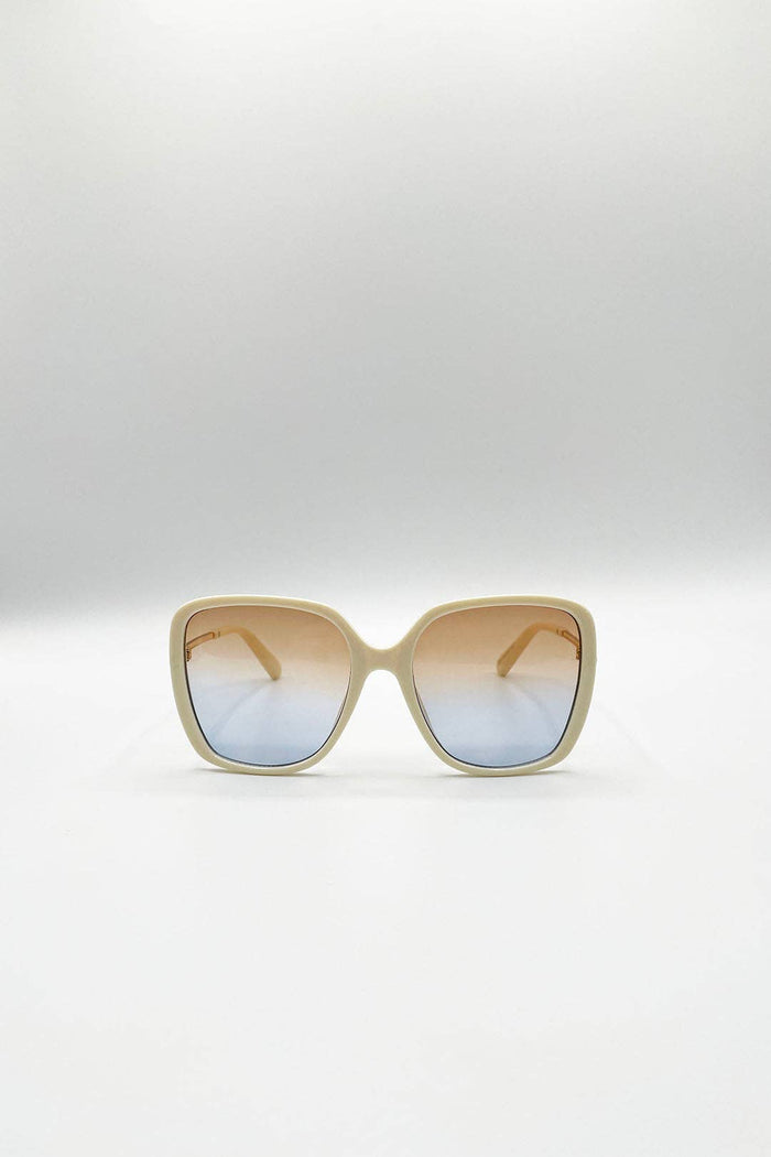 Oversized square sunglasses with a beige frame and gradient lenses that fade from warm tan at the top to light blue at the bottom, shown on a neutral light gray background.