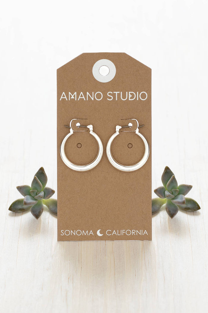 Pair of silver hoop earrings on a 'Amano Studio' branded card with succulents in the background.