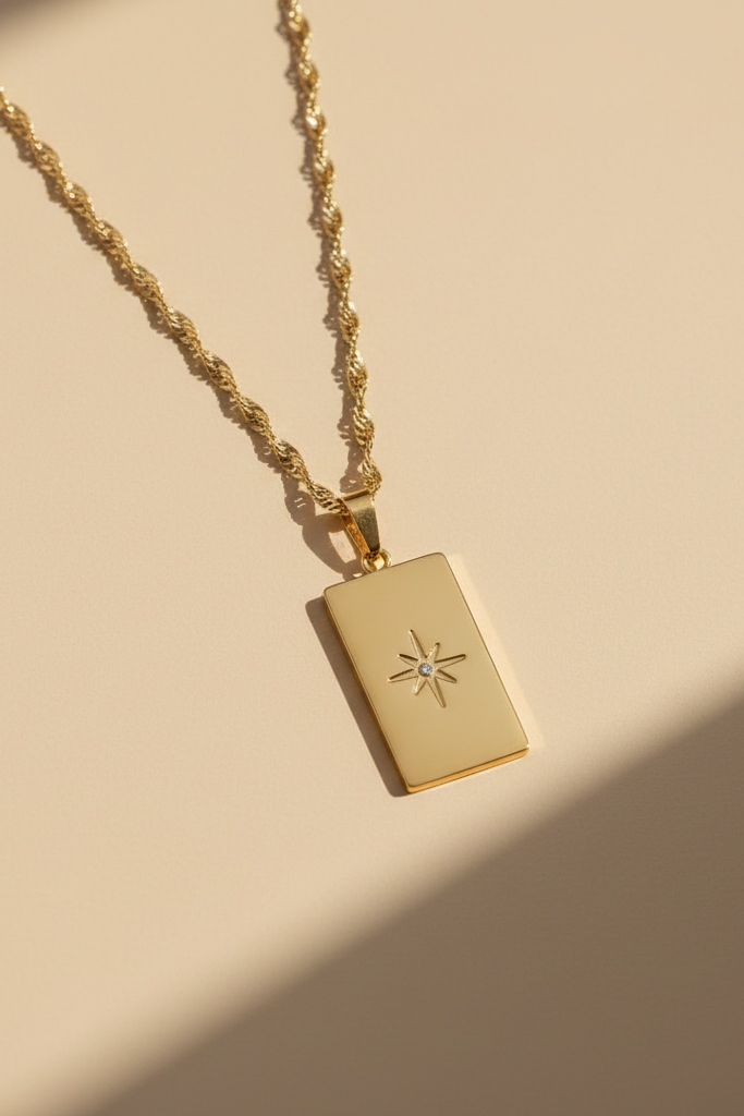 Gold necklace with a rectangular pendant on a beige background