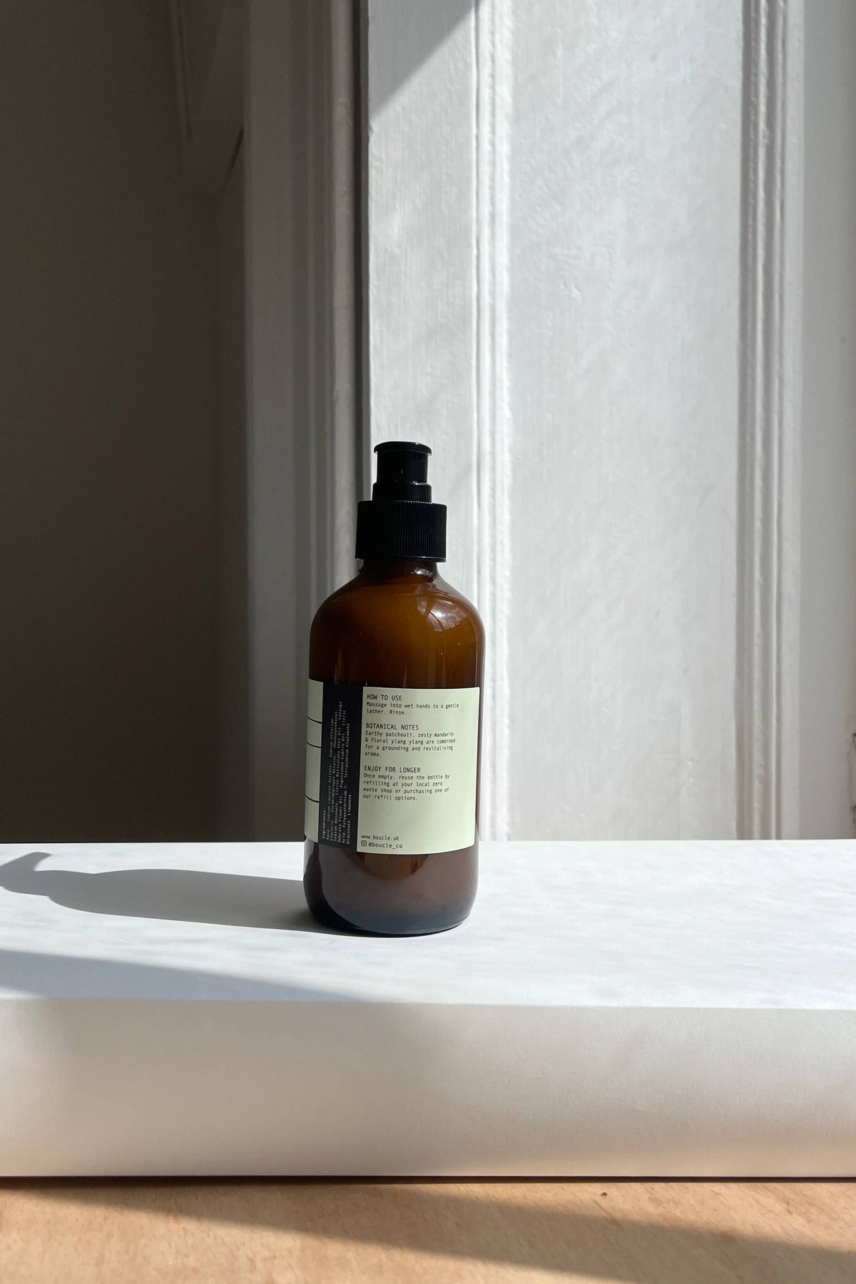 Brown bottle with a label on a white surface near a window