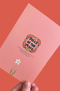A hand holds a textured pink card featuring a retro-style illustration of a flower and the text 'PIECE OF THE BEACH' against a solid coral background.