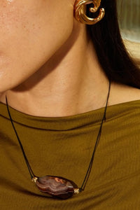 Close-up of a necklace with a large pendant and gold accents worn by a person.