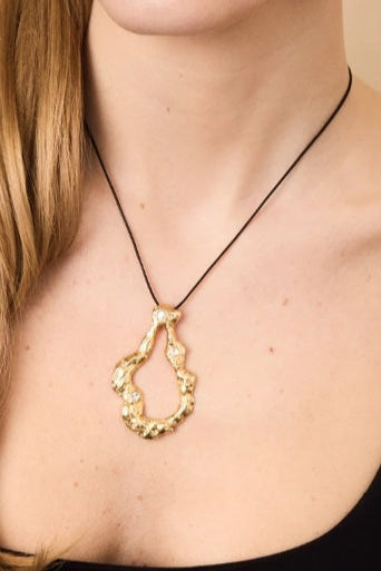 Gold necklace with a unique pendant worn by a person