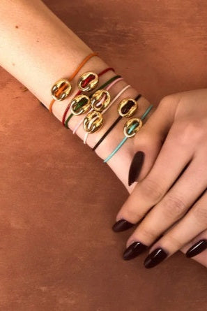 Hand wearing multiple bracelets on a brown surface