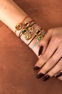 Hand wearing multiple bracelets on a brown surface