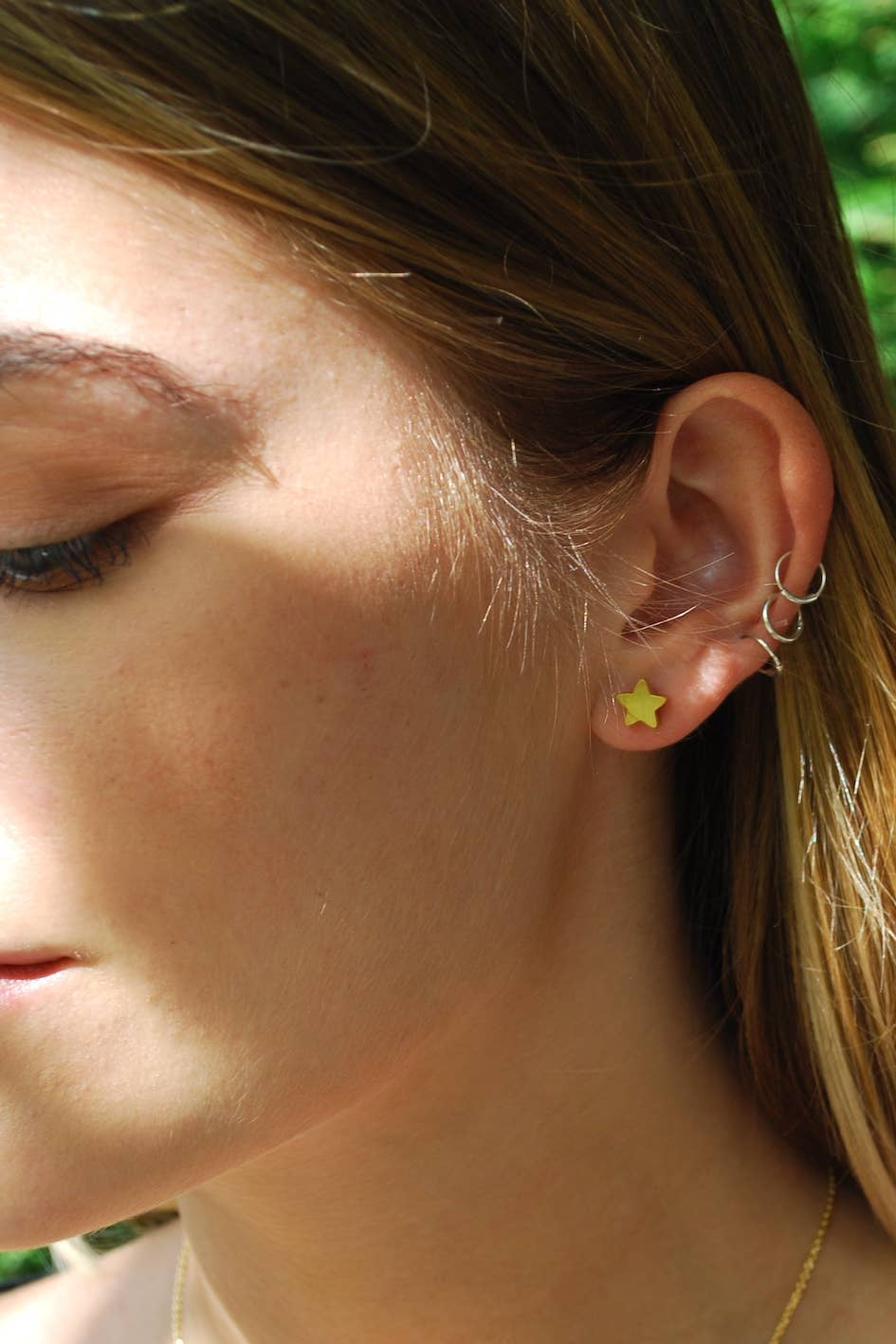 Close-up of a person wearing a star-shaped earring with a natural background