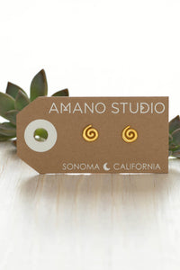 Gold spiral earrings on a 'Amano Studio' branded card with succulents in the background