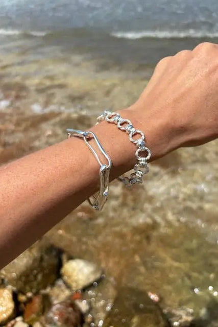Silver bracelets on a wrist with a beach background