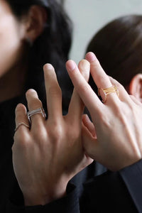 Two people wearing rings on their fingers, with a blurred background