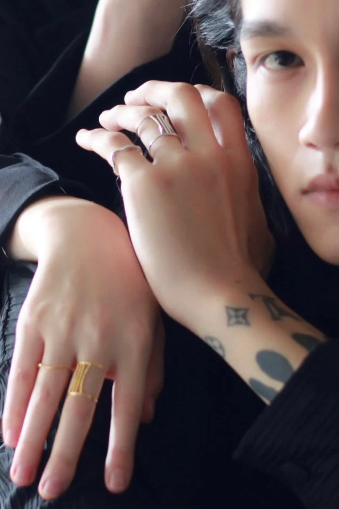 Close-up of a person's hands with gold rings, one hand resting on the other.