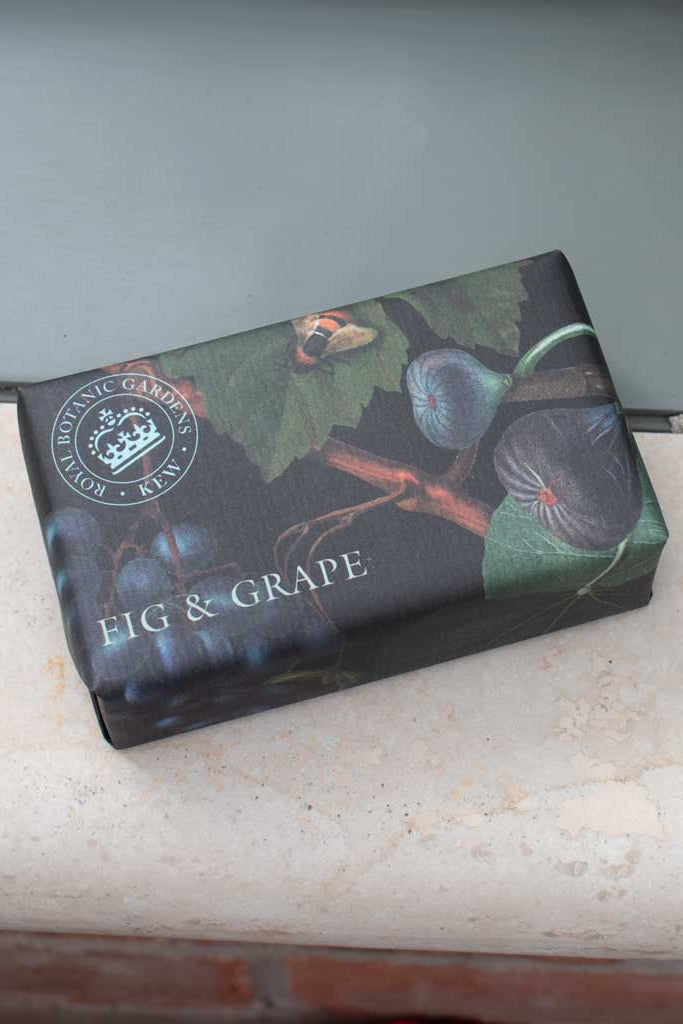 Box of fig and grape-flavored product on a stone surface with a neutral background