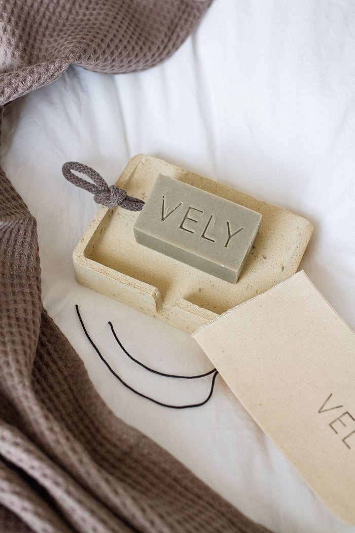 Bar of soap with 'VELY' branding in a box on a soft surface