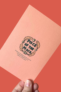 A hand holds a peach-colored textured card featuring a black and gold illustration of a peach and the words 'Piece of the Peach' against a solid coral background.