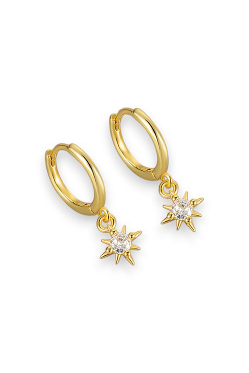 A pair of gold huggie hoop earrings with dangling star-shaped charms set with clear gemstones, shown on a plain white background.