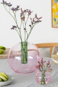 Pink glass vase with flowers on a table with limes and cookies