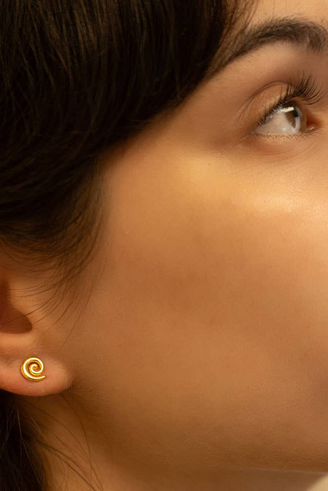 Close-up of a woman wearing a gold spiral earring.