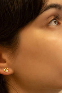 Close-up of a woman wearing a gold spiral earring.