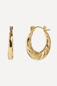 Gold hoop earrings on a light beige background