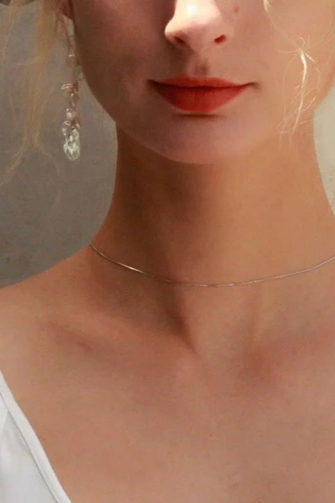 Close-up of a woman wearing a white tank top with a neutral background
