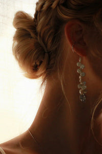 Close-up of a person wearing a delicate earring with a soft, blurred background
