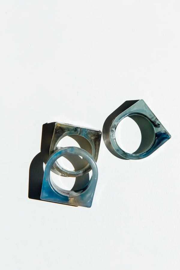 Three metallic geometric rings on a light gray background