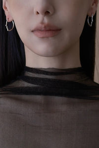 Close-up of a person wearing a sheer black top with a neutral background
