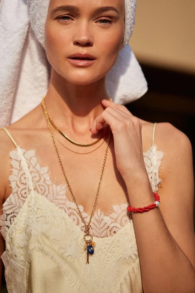 Woman wearing a white lace top and gold necklace with a blurred background