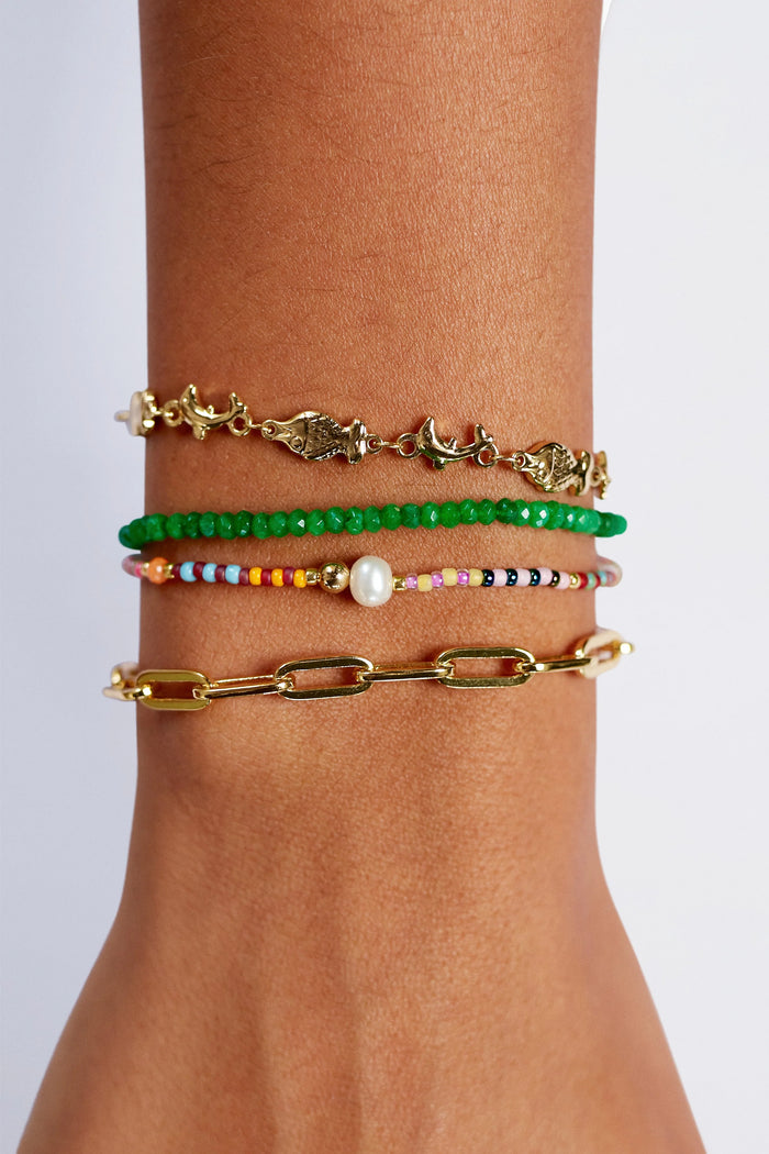 Three bracelets on a wrist against a light gray background