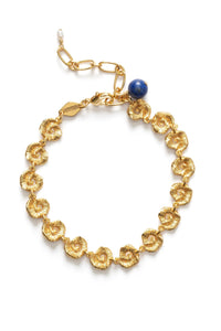 Gold bracelet with shell designs and a blue gemstone on a white background