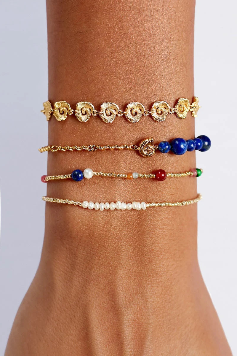 Multiple bracelets on a wrist against a neutral background